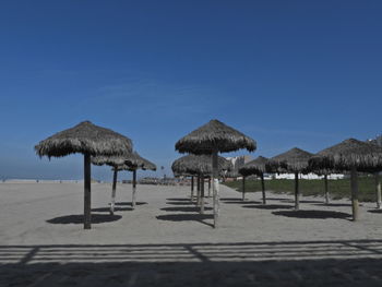 Parasols on beach against clear blue sky