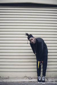 Portrait of young man standing against closed shutter