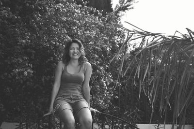 Portrait of smiling woman sitting against plants