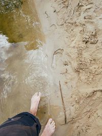 Low section of man standing by water