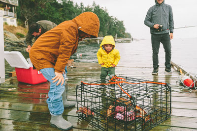 Family catching fish while standing on pier over lake