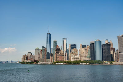 Buildings by sea against clear blue sky