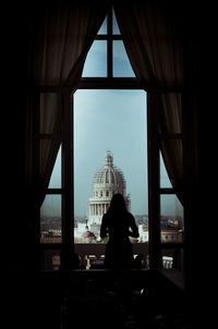 Silhouette person standing by window against historic church