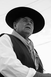 Portrait of man wearing hat standing against white background