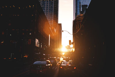 Traffic on city street and buildings at sunset