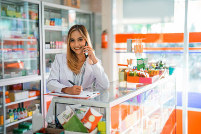 Young woman using mobile phone while standing in store