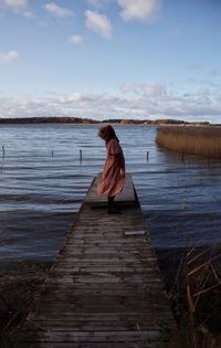 Rear view of woman on lake against sky
