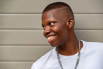 Young smiling man looking away against wall