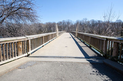 Footbridge over road against clear blue sky