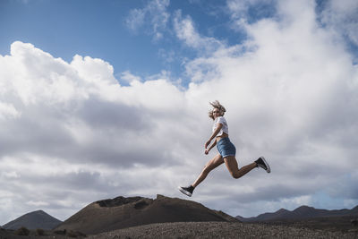 Young woman running against sky at volcano el cuervo, lanzarote, spain