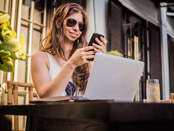 Smiling young woman using mobile phone in office