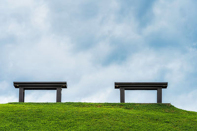 Bench on field against sky