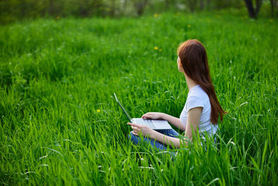 Rear view of woman sitting on grassy field