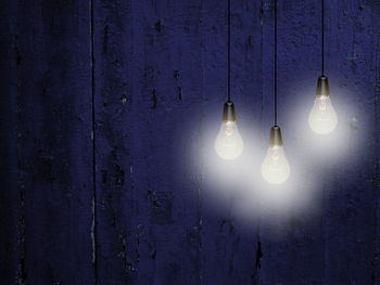 Illuminated light bulbs against purple wooden wall