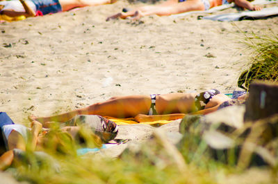 Low section of young woman relaxing at beach on sunny day