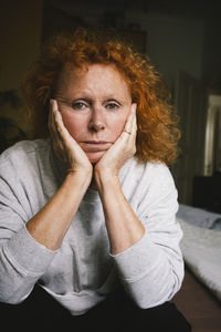 Portrait of depressed senior woman sitting with head in hands at home