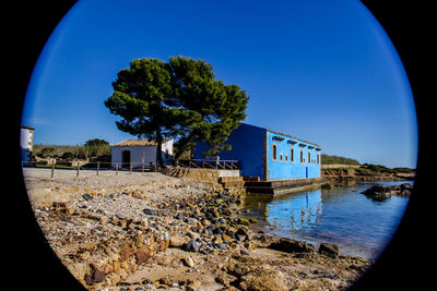 Scenic view of river by buildings against clear blue sky