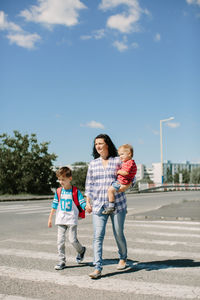 Full length of father and daughter standing on field against sky