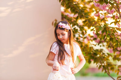 Smiling girl standing against flowering tree