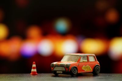 Close-up of toy car and traffic cone on table against defocused background