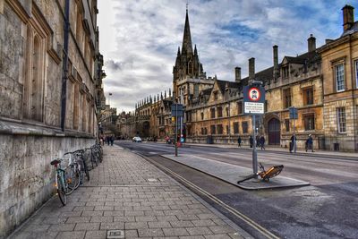 View of street and oxford university buildings  in oxford, england, against cloudy sky