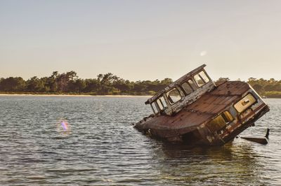 Abandoned boat in sea against clear sky