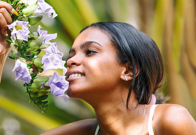 Close-up portrait of young woman with pink flower