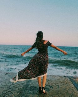 Rear view of woman standing on beach against sea