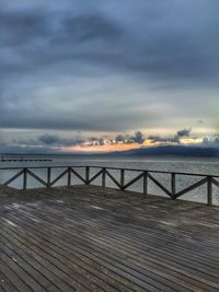 Pier on sea against cloudy sky