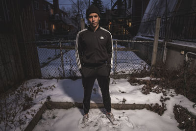 Full length portrait of young man standing in snow