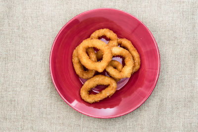 Directly above shot of onion rings served in plate on jute fabric