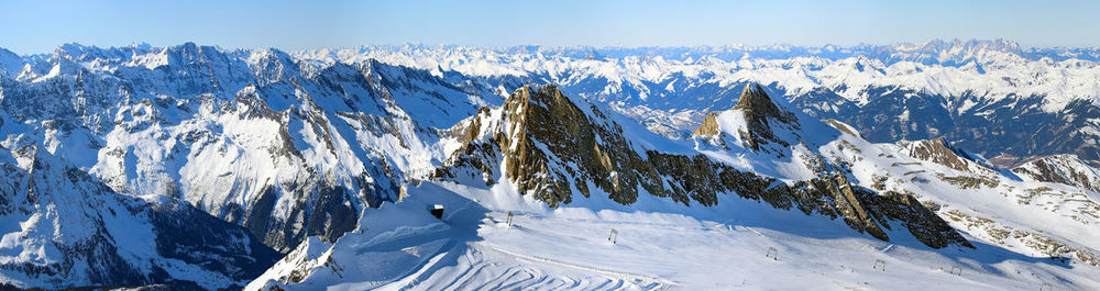 Wide angle aerial panorama of sunny austrian alps in winter with skiing tracks near zell am see lake