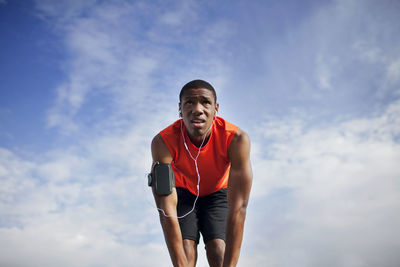 Low angle view of man exercising against cloudy sky on sunny day