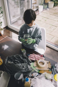 High angle view of boy holding glass container at home