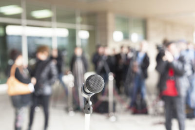 Close-up of microphone with people standing in background