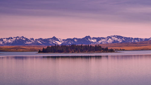 Scenic view of lake by mountains against sky during sunset