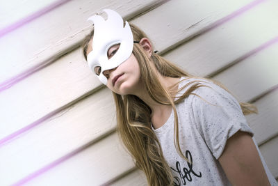 Portrait of teenage girl wearing mask against wall