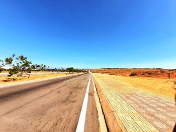 Road against clear blue sky