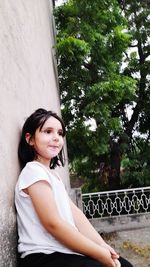 Portrait of young woman standing against trees