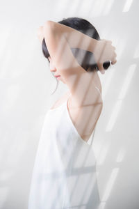 Digital composite image of woman standing against white wall