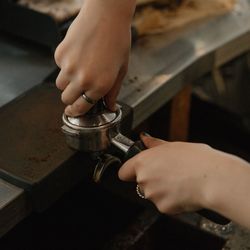 Cropped hands of woman preparing coffee in cafe