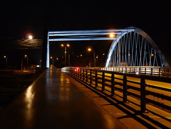 Illuminated bridge over river against sky at night