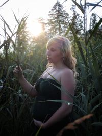 Young woman looking away while sitting on land