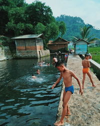 People standing on riverbank against trees