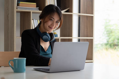 Young woman using mobile phone while sitting on table