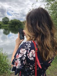 Rear view of woman photographing with mobile phone