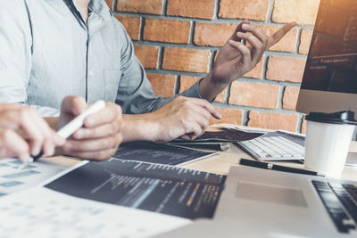 Midsection of man using mobile phone while sitting on table