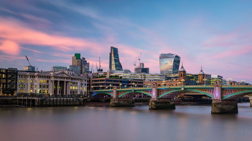 Bridge over river in city against sky