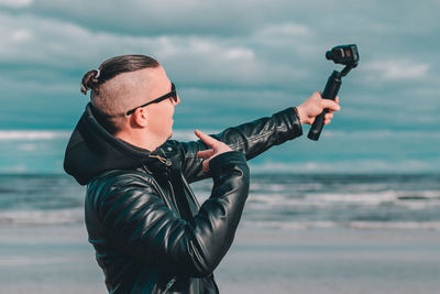 Man holding camera while standing on beach