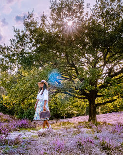 Woman standing by tree against plants